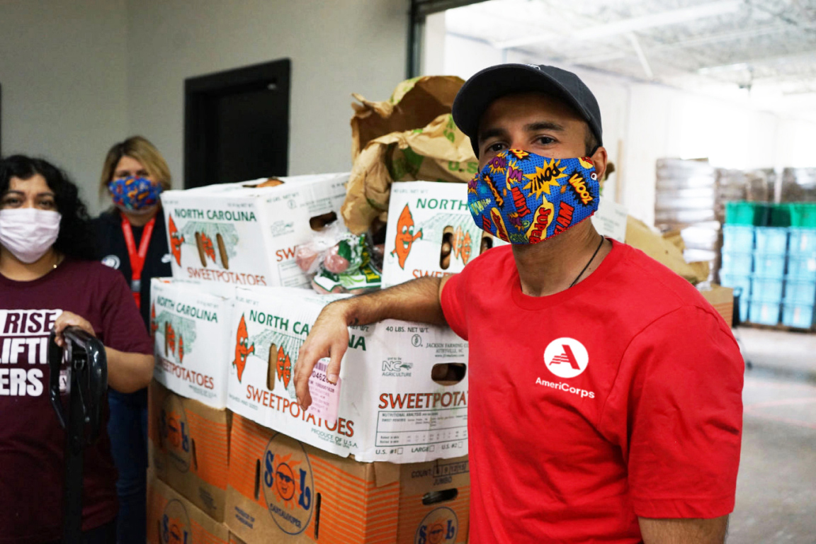 Man wearing a face mask standing next to crates of food