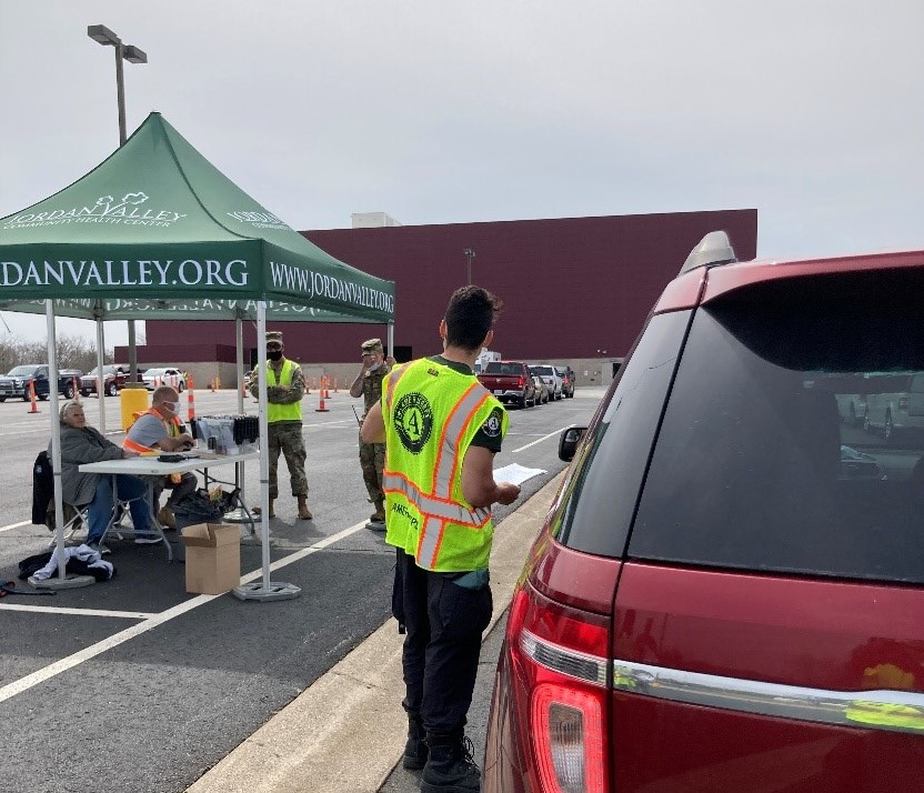 AmeriCorps member stands beside a car