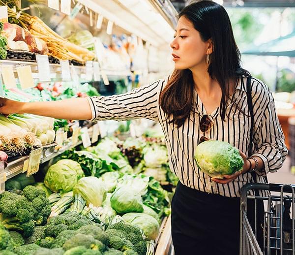 Woman in a grocery store looking at vegetables