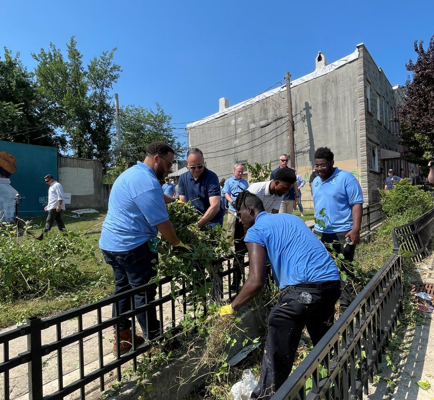Second Gentleman Douglas Emhoff, AmeriCorps CEO Michael D. Smith and Baltimore Mayor Brandon Scott weed an old rain garden with Civic Works AmeriCorps Members in Baltimore.