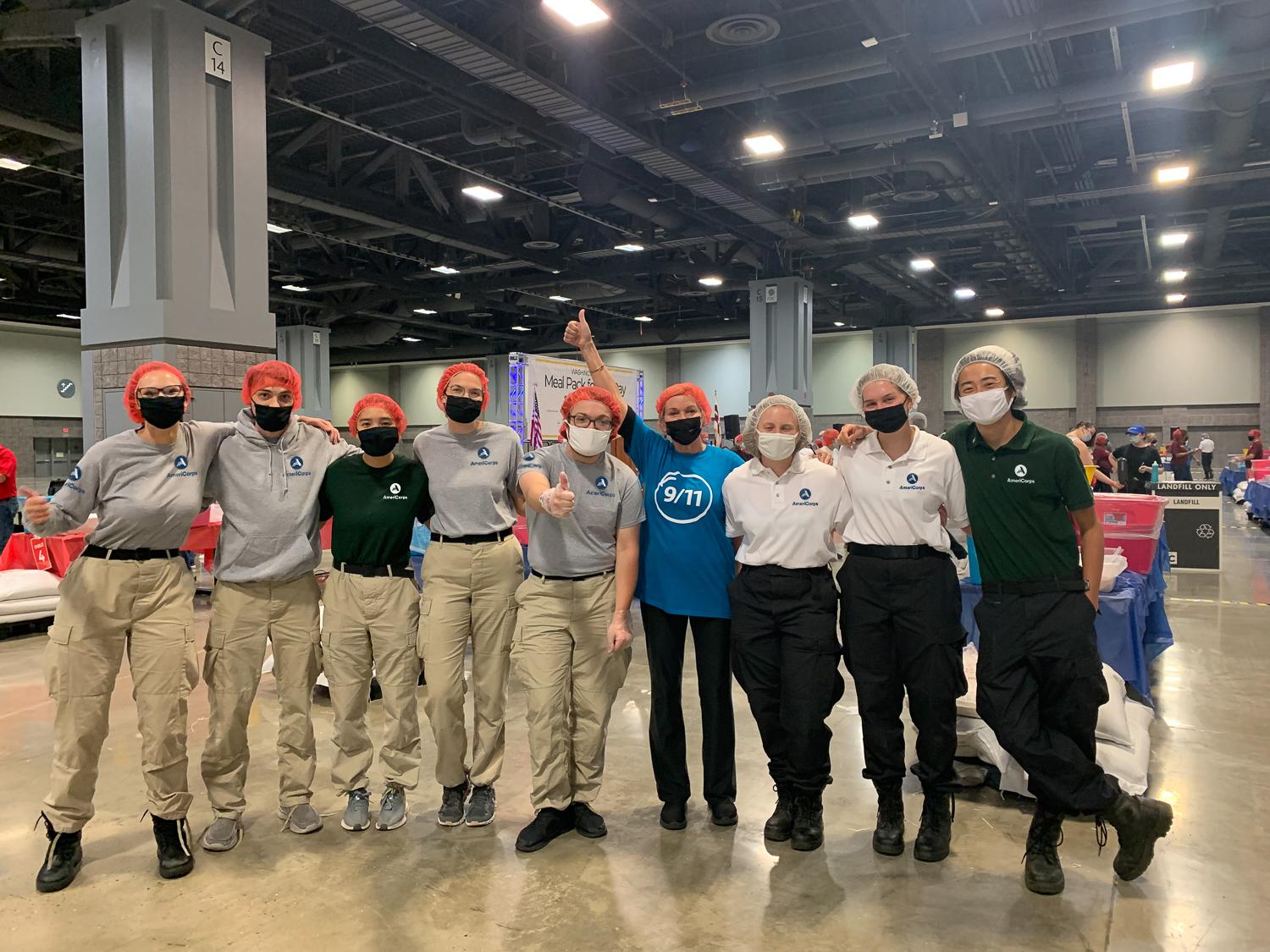 AmeriCorps members and volunteers smiling on 9/11 Day at a food packing event.
