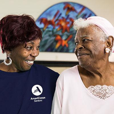 Two women looking at each other one wearing an AmeriCorps Seniors top