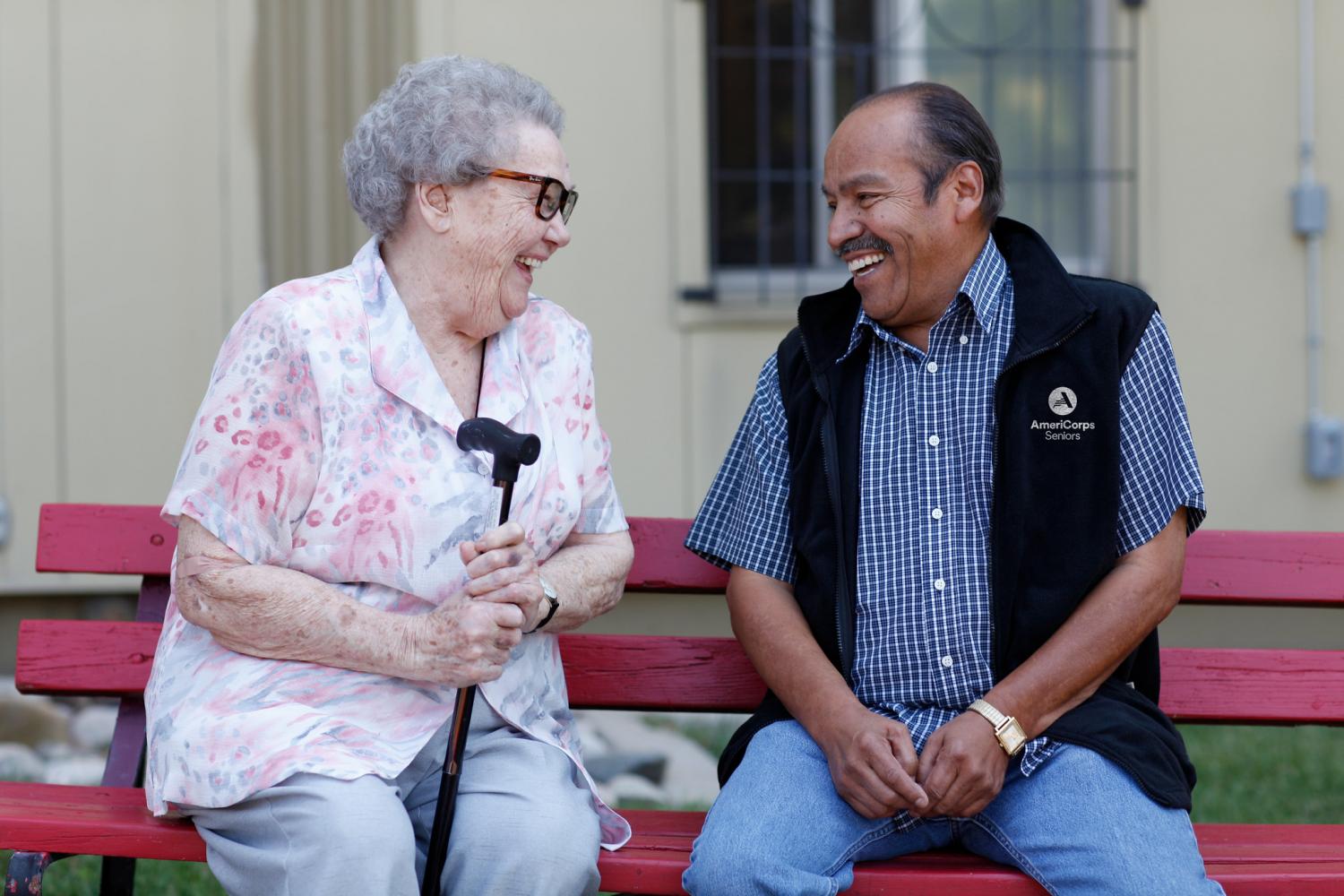An AmeriCorps Seniors volunteer talks to a smiling woman