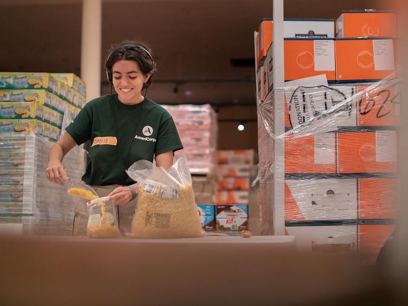 AmeriCorps member packaging food for a food bank.