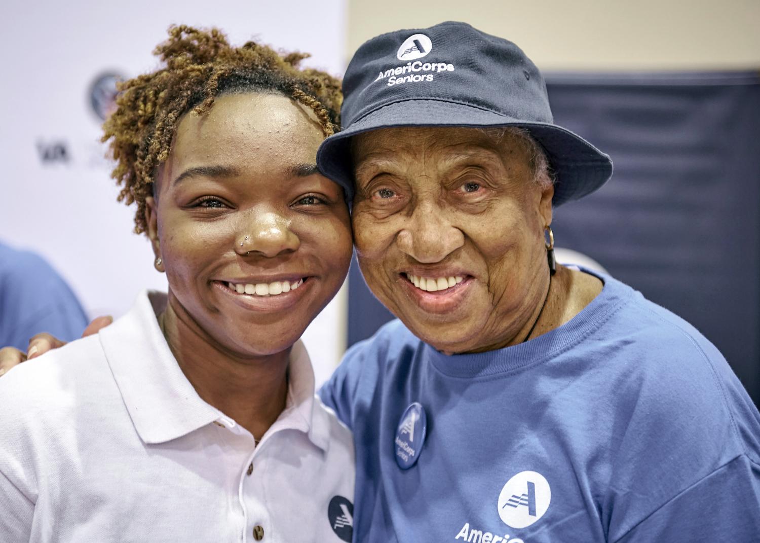 A young AmeriCorps member smiling with an AmeriCorps Seniors volunteer