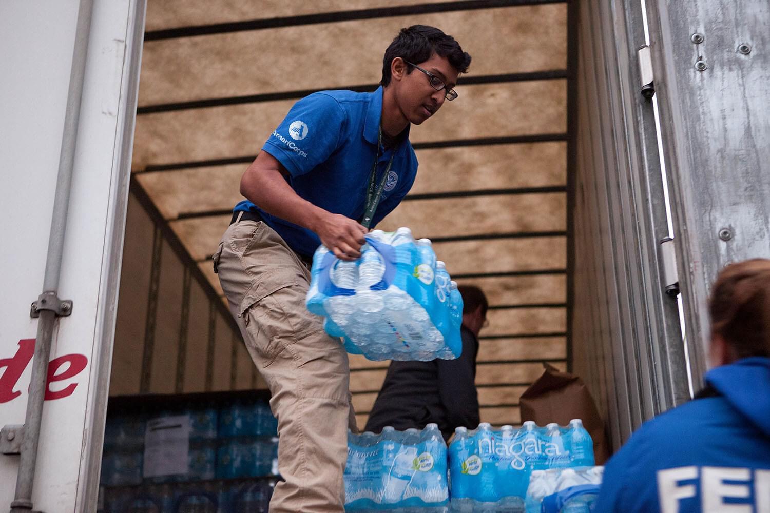 AmeriCorps volunteer carrying bottled waters
