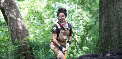 Woman wearing an AmeriCorps T-shirt working in a wooded area
