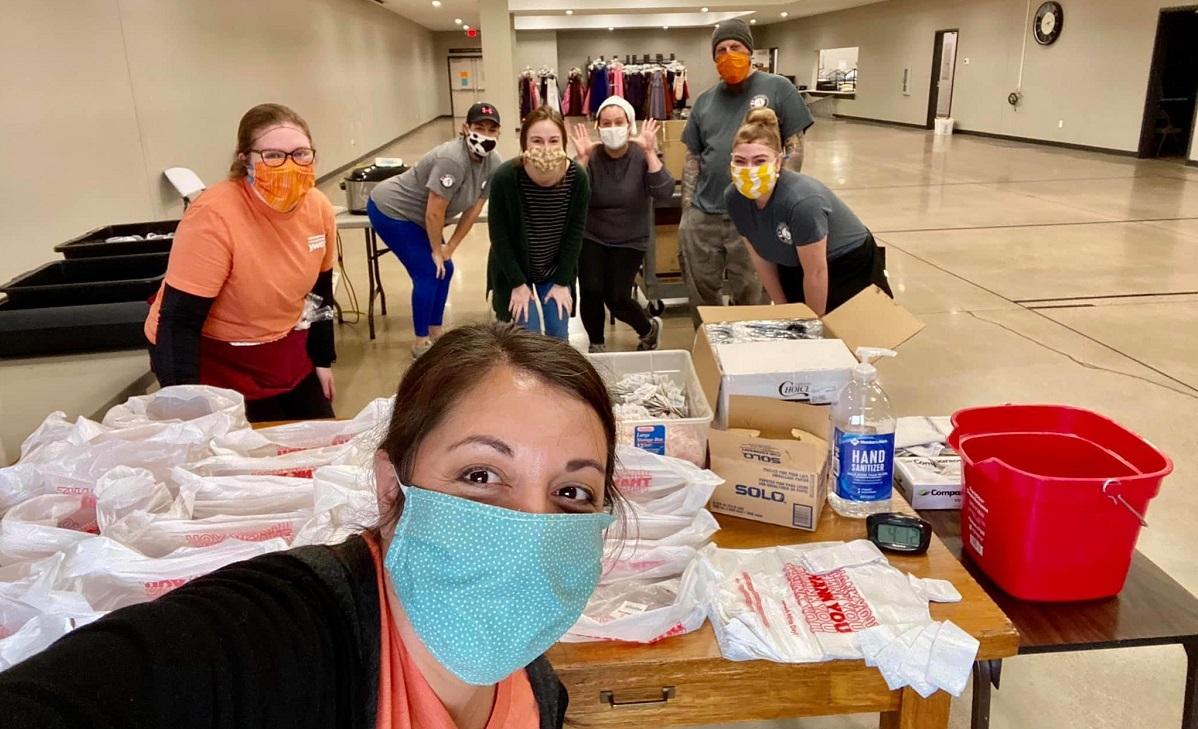 AmeriCorps members with safety masks stop to pose as they prepare care packages